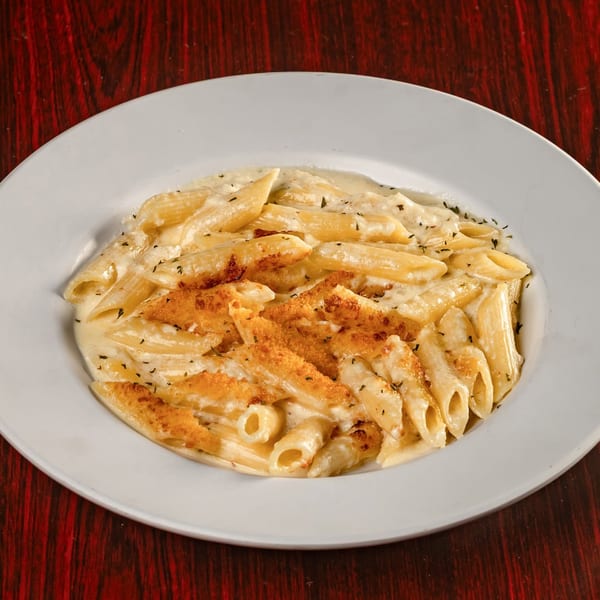 Creamy penne pasta with toasted breadcrumbs and herbs on a white plate.